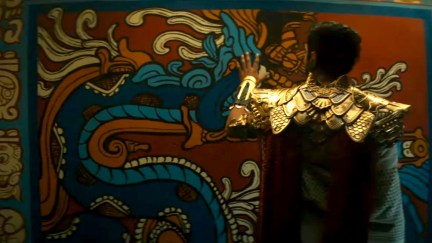 A still from Black Panther: Wakanda Forever in which we see someone from behing (probably Namor) looking at an Aztec-styled wall.