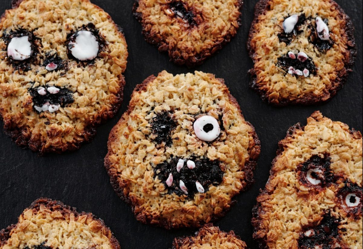 Cookies with scary faces are laid out on a black background.