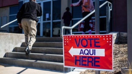 People enter a building with a sign outside reading Vote (aqui) here