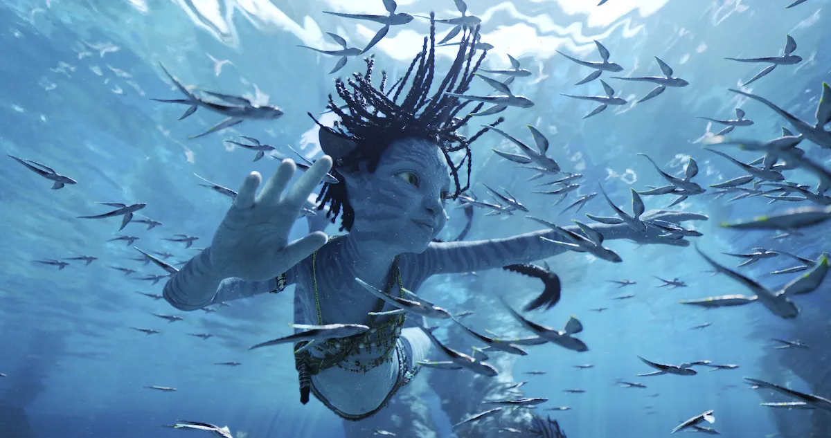A Na'vi swimming underwater, surrounded by fish
