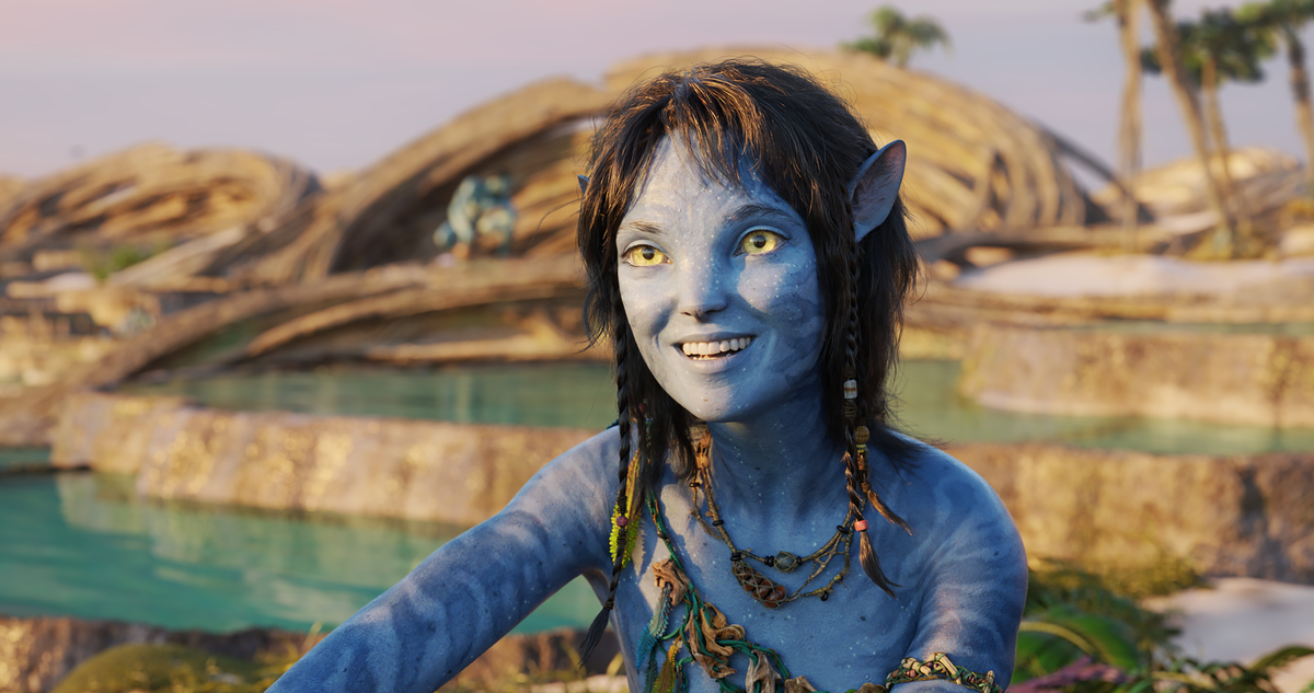Kiri smiles with a village in the background in Avatar: the Way of Water.