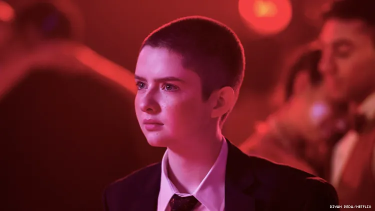 Lachlan Watson as Theo in The Chilling Adventures of Sabrina, frowning in red light.