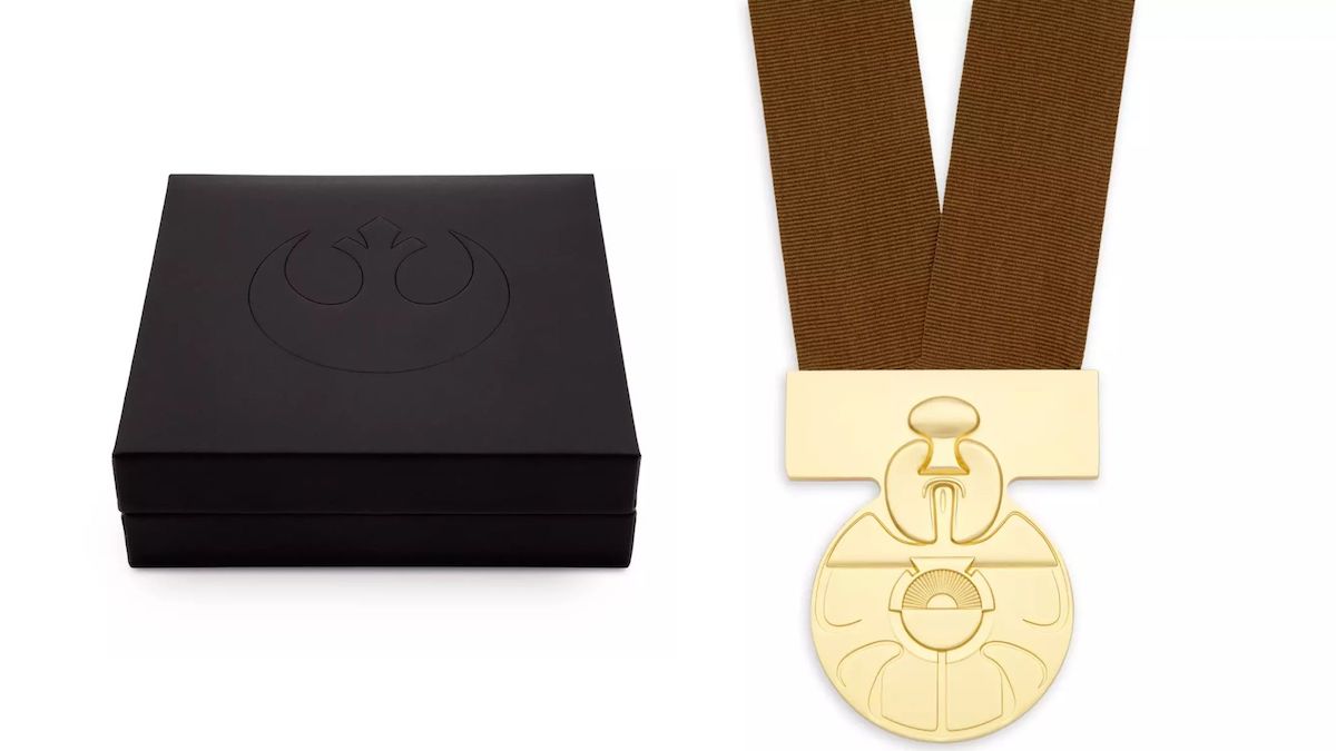 A gold medal on a brown lanyard designed to resemble the Medal of Yavin from 'Star Wars', next to a black display case