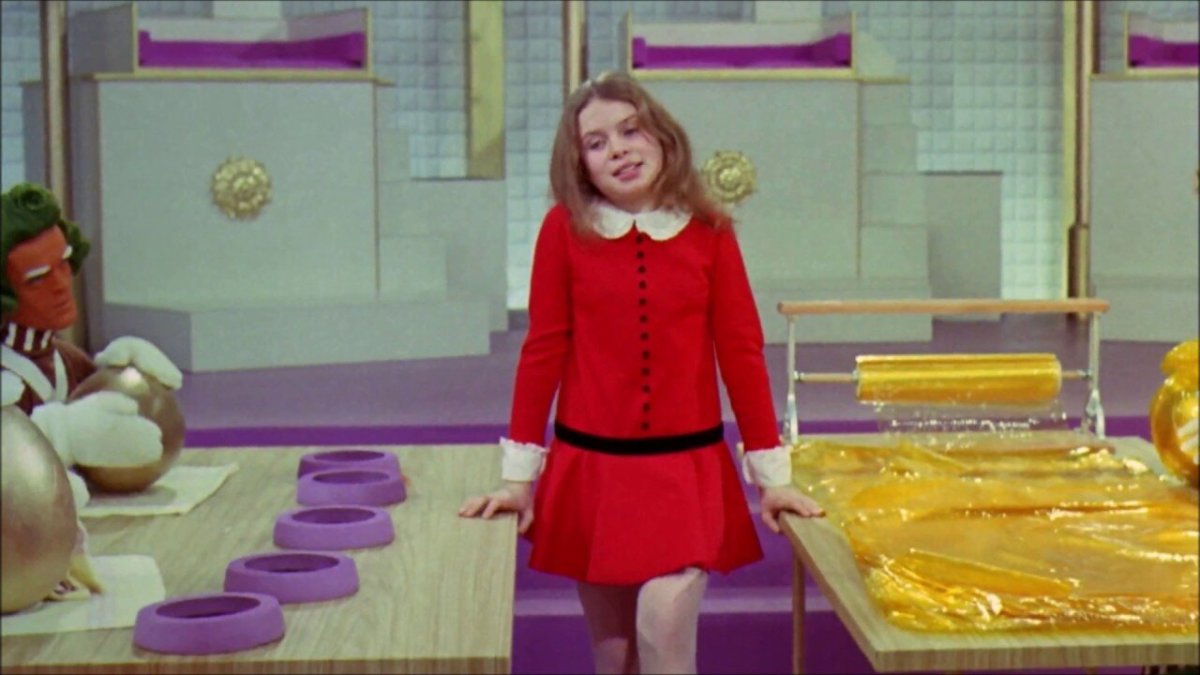 Veruca Salt walks between the rows of candy