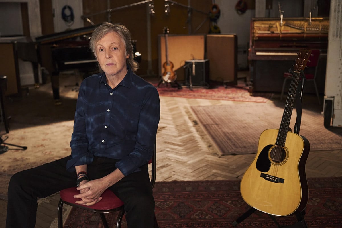 Paul McCartney sitting with a guitar in 'If These Walls Could Sing'