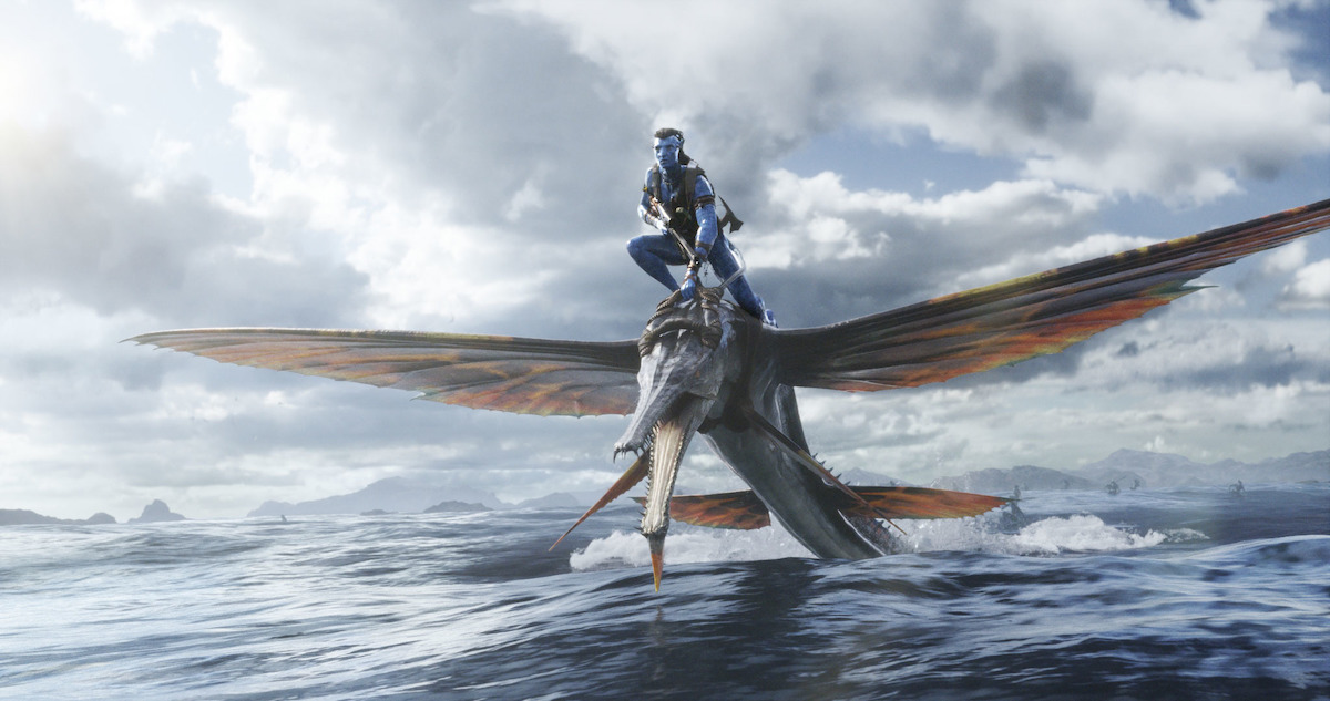A Na'vi emerging from a body of water riding on the back of a tulkun
