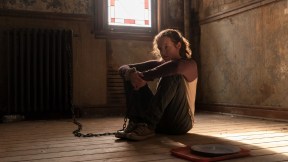 In a scene from 'The Last of Us,' Ellie (Bella Ramsey) sits alone in a mostly empty room, her ankle shackled to a radiator.