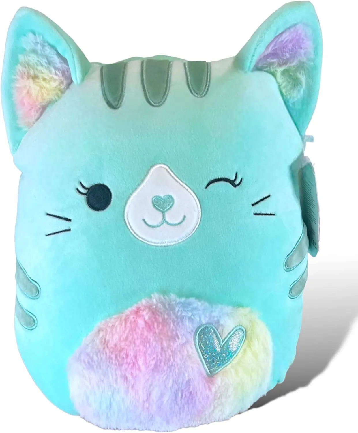 A teal tabby cat squishmallow with a rainbow stomach and a winking face. There's a heart on her stomach.