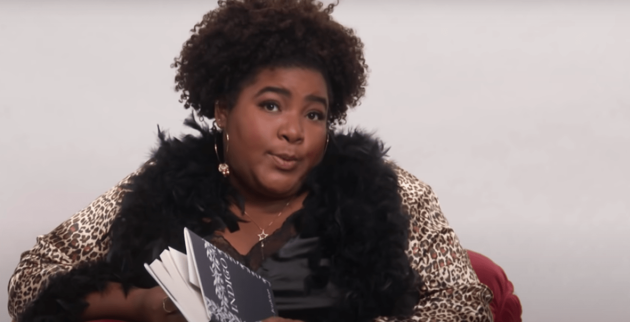 Comedian Dulce Sloan reads a copy of 'Indigo' while sitting on a sofa and wearing romantic negligee during a segment on 'The Daily Show'