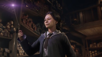 A wizard looks at her wand as the tip glows in 'Hogwarts Legacy'