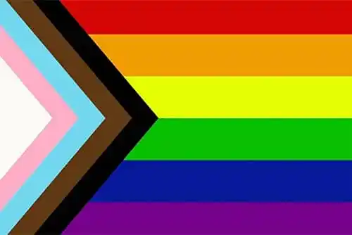 The progress pride flag: a triangle made of white, pink, light blue, brown, and black stripes against the horizontal rainbow stripes of the traditional pride flag