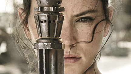 Extreme close-up of Rey from Star Wars, played by Daisy Ridley, partially obscuring her face with her lightsaber hilt