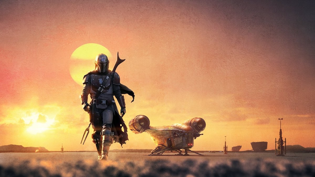 The bounty hunter Din Djarin (Pedro Pascal) walks in front of a sunset in key art for 'The Mandalorian'