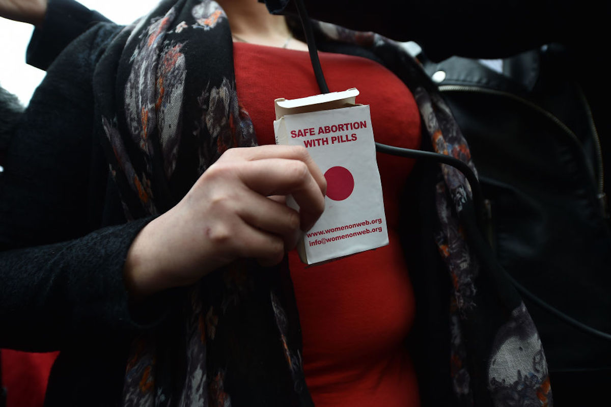 A woman holds an abortion pill packet in front of her