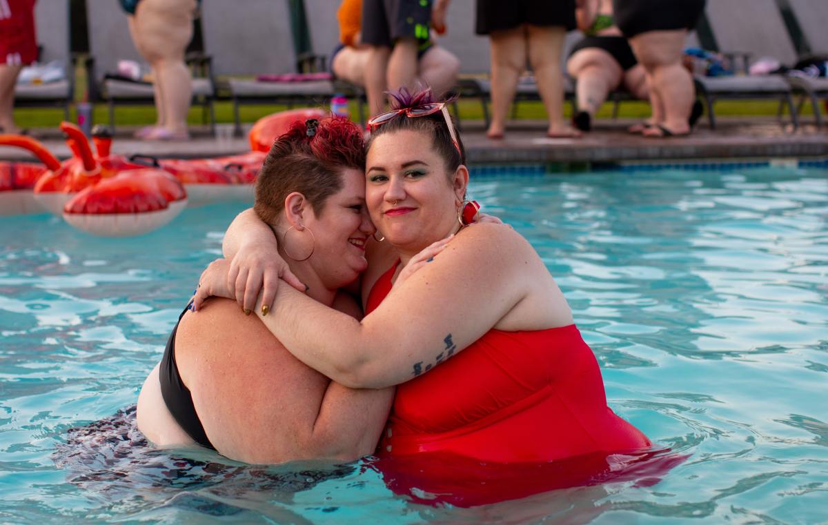 Two fat women embrace in a swimming pool