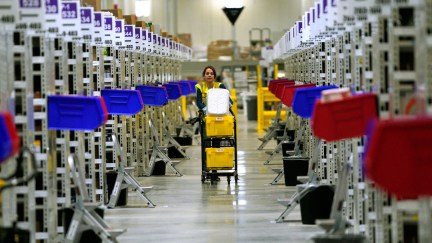 A worker moves down an aisle inside an Amazon fullfillment center.