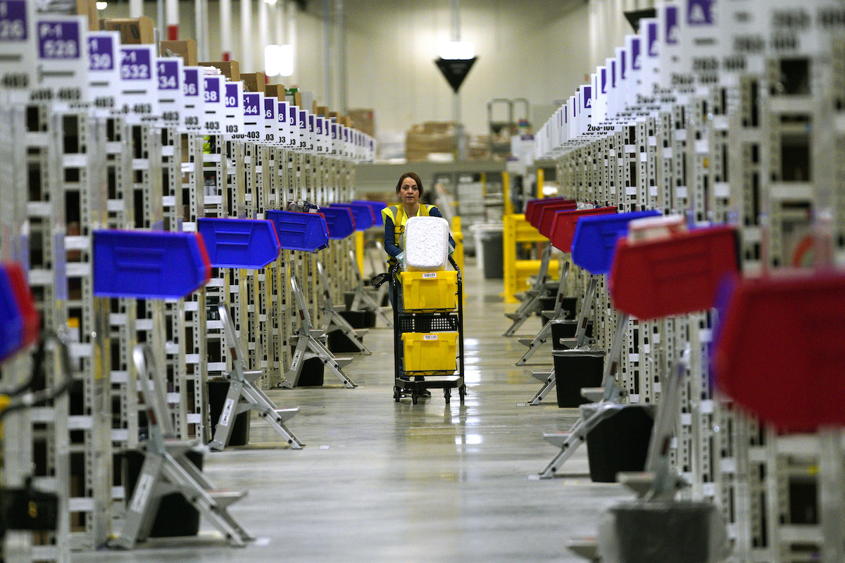 A worker moves down an aisle inside an Amazon fullfillment center.
