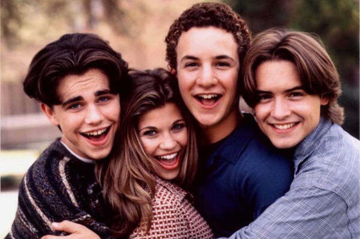 The cast of Boy Meets World poses, grinning at the camera.
