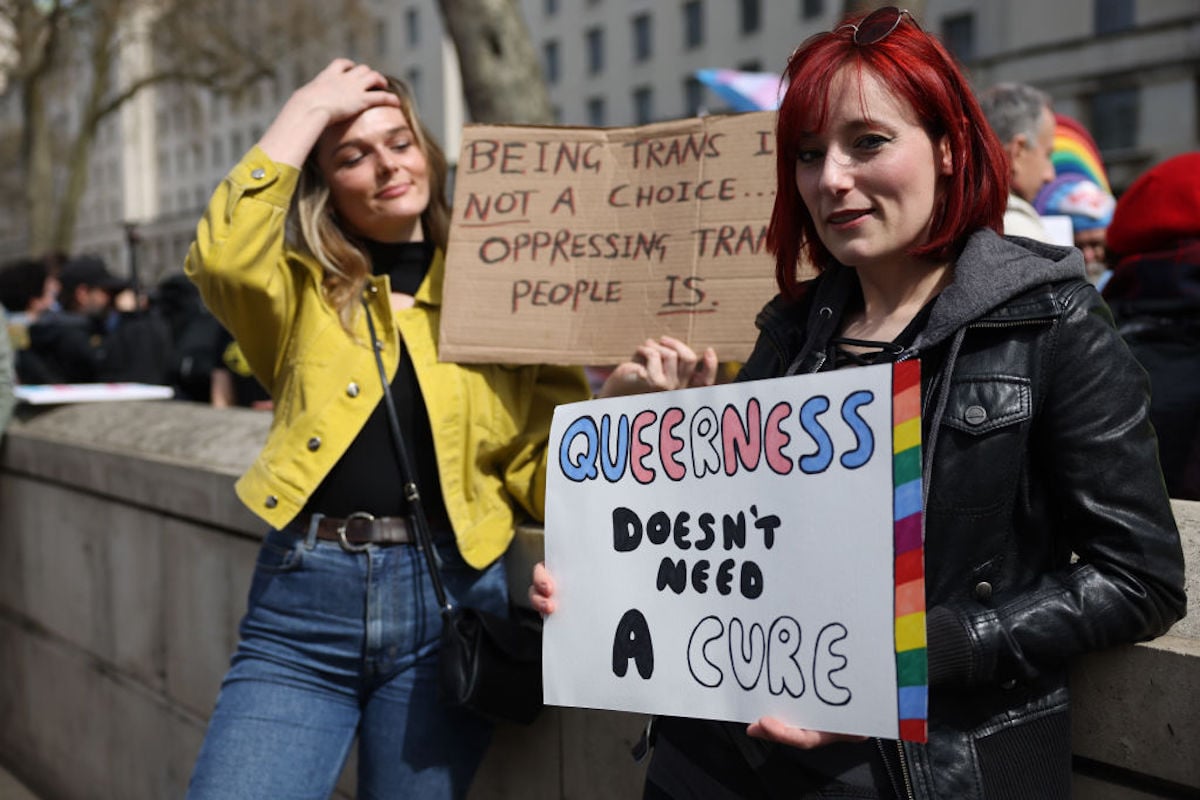 Protesters hold signs advocating against conversion therapy.