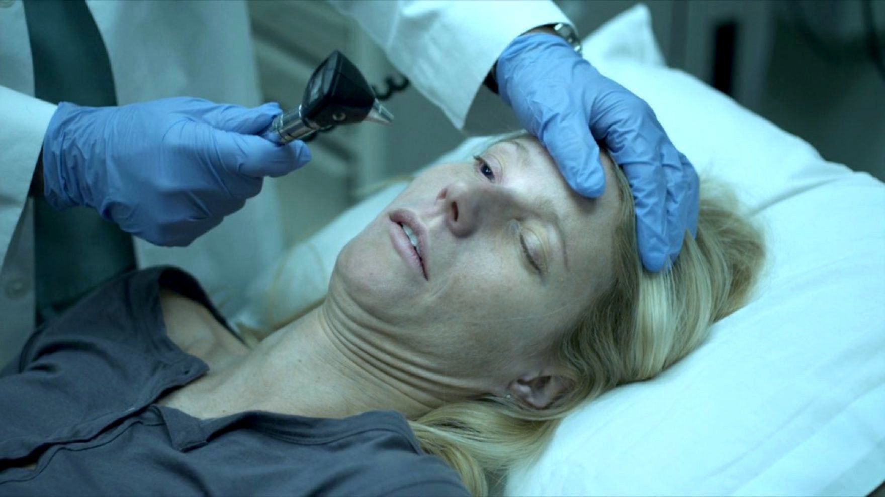 Gwyneth Paltrow lies on an exam table with one eye held open by a doctor in Contagion.