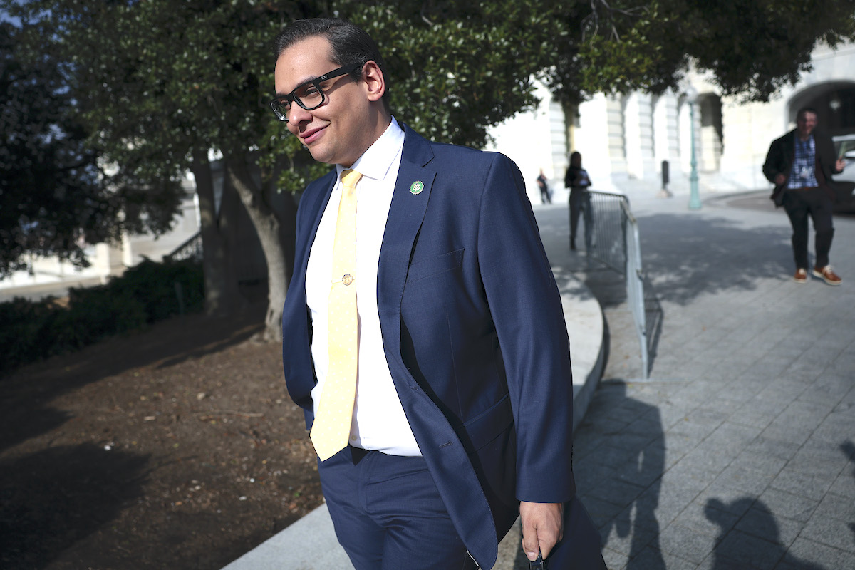 George Santos smiles to himself while walking outside.