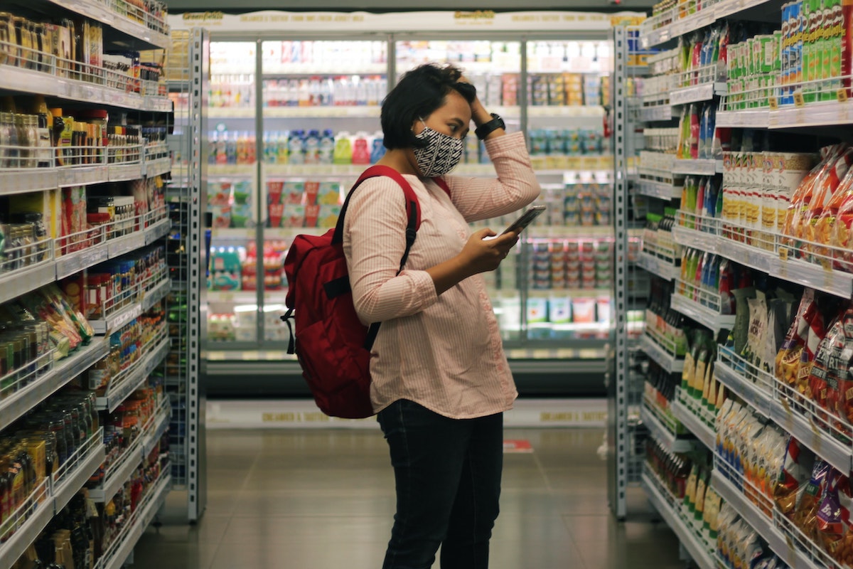 A woman looks confused in a grocery store aisle.