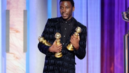 Jerrod Carmichael holds three Golden Globes statues in his arms.
