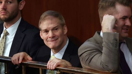 Jim Jordan bites his lip and cringes while clinging a railing in the House.