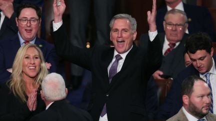 Kevin McCarthy raises his arms and grins, surrounded by Republicans on the House floor.