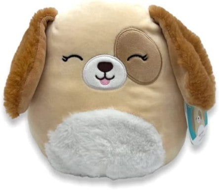 A tan dog Squishmallow with long ears and a patch over one eye, doing a blep
