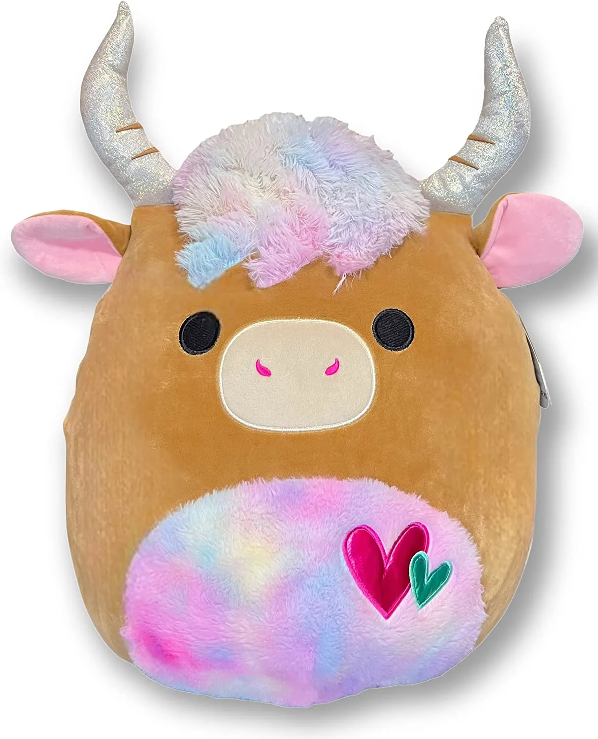 Brown cow Squishmallow with shiny horns, a rainbow stomach and fringe and hearts on that stomach