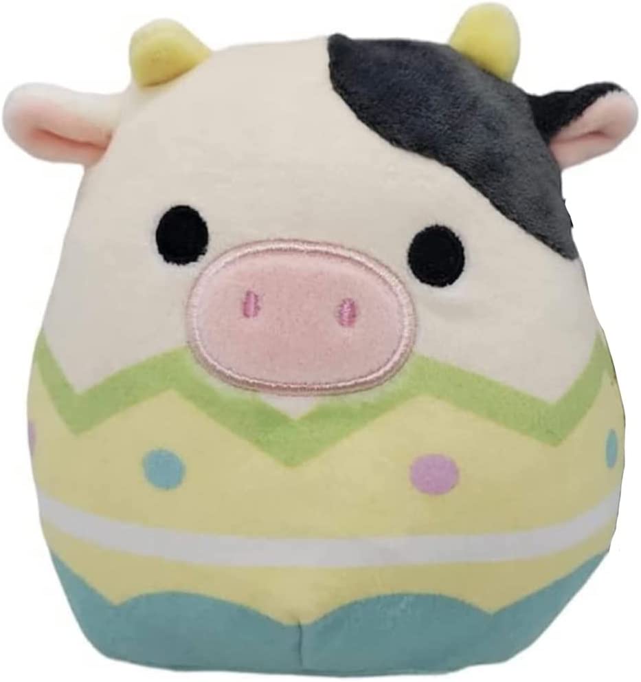 A black and white cow Squishmallow in a yellow egg shell