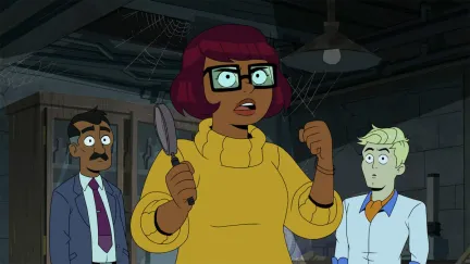 Velma holds a frying pan with Fred and Velma's father in the background.
