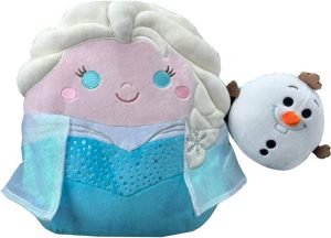 A blonde human Squishmallow in a blue dress, holding a smaller snowman Squishmallow