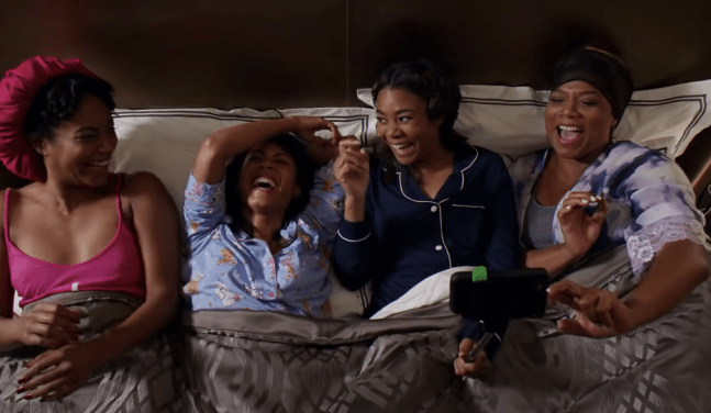 Four women lay in a hotel bed together