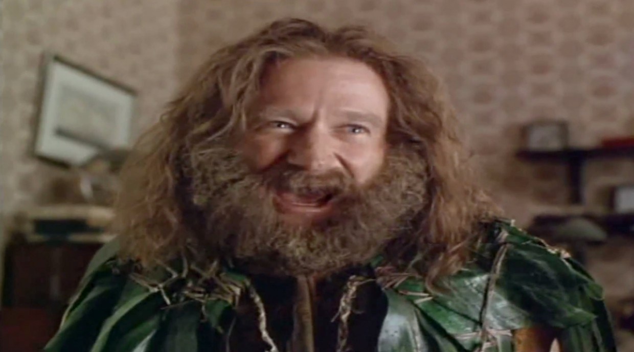 Robin Williams in Jumanji, wearing leaves and a big beard. A still from the "What year is it?!" meme.