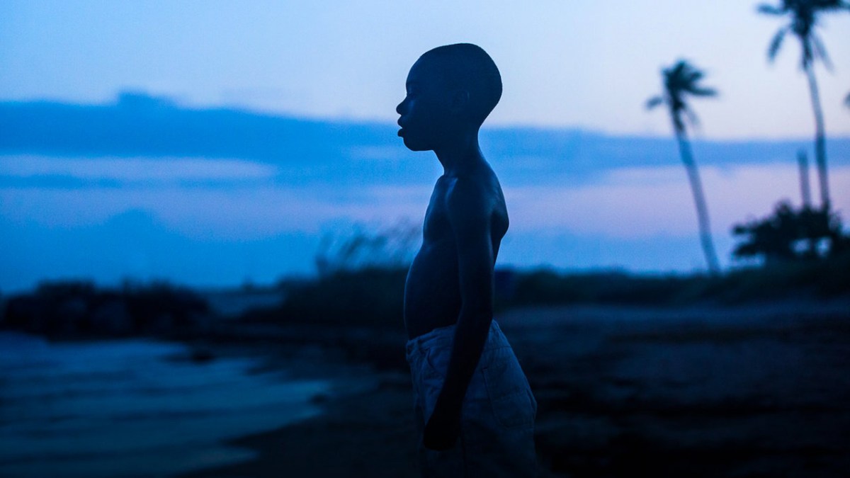 A young boy looks out into the water on a beach, with a sunrise background, from the movie, Moonlight.