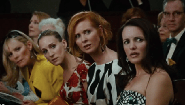 Carrie Bradshaw, Samantha Jones, Charlotte York, and Miranda Hobbs sit at an auction