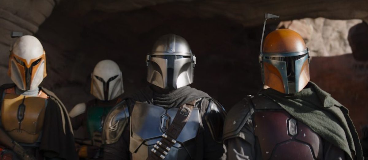 Din Djarin and three other Mandalorians standing together, ready for battle