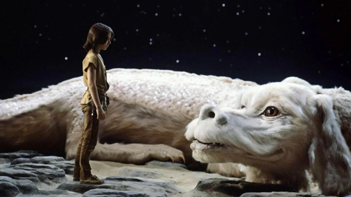 A still from the film The NeverEnding Story depicting Noah Hathaway as Atreyu standing in front of the luck dragon Falkor under a starry sky