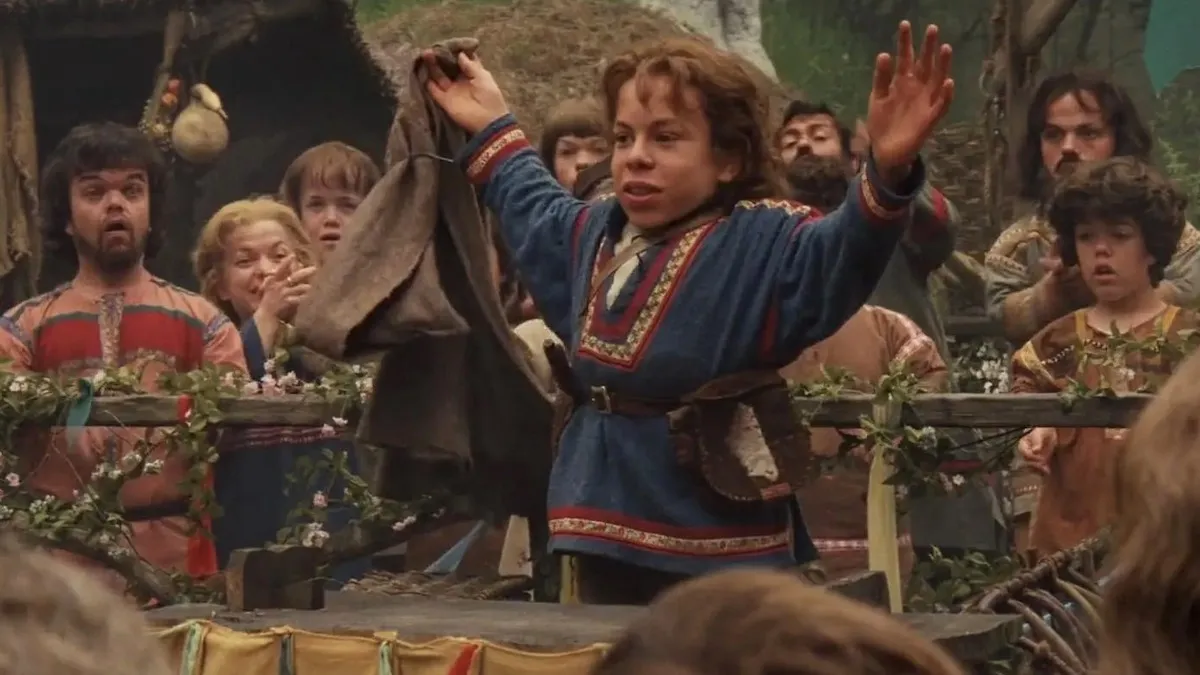 Warwick Davis as Willow in the film Willow raising his arms triumphantly among his fellow villagers