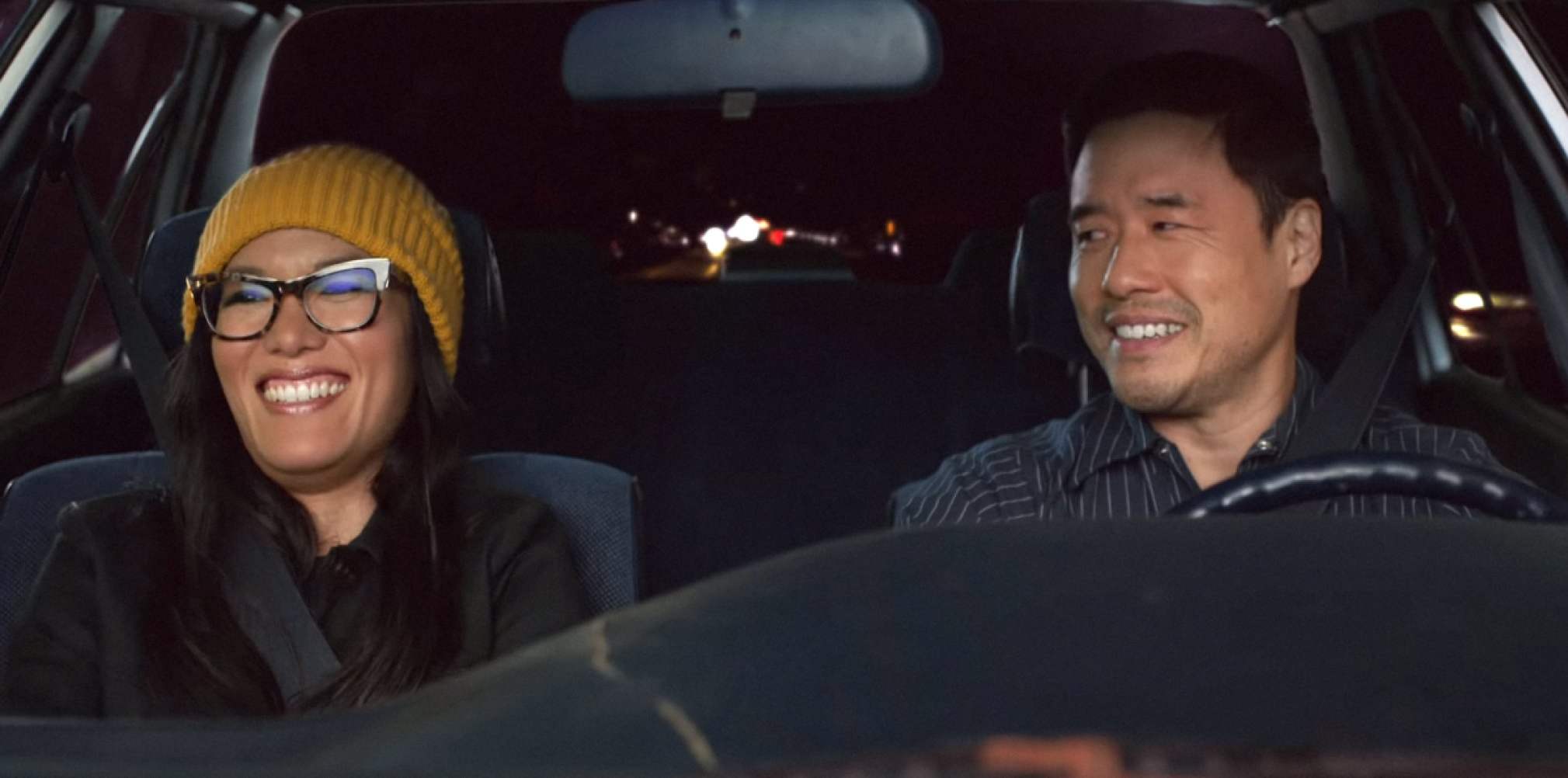 Ali Wong and Randall Park sit in the car, laughing and smiling at one another in the movie Always Be My Maybe.