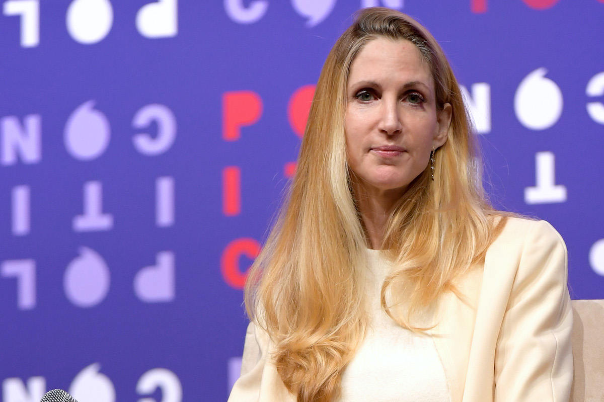 Ann Coulter looks at the camera with a terse expression in front of a backdrop bearing the Politicon logo