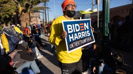 An immigration rights protester holds a Biden/Harris campaign sign with a handwritten tag reading 