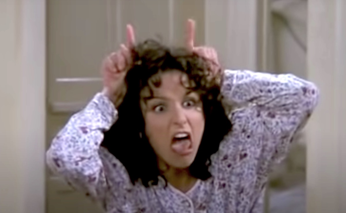 Elaine mimes devil horns on her head in Seinfeld.