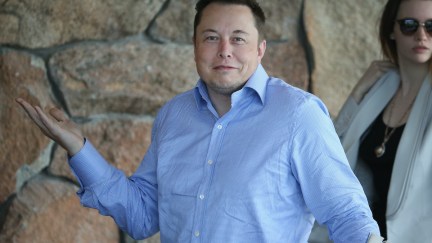 Elon Musk looks at the camera and gives an exaggerated shrug.