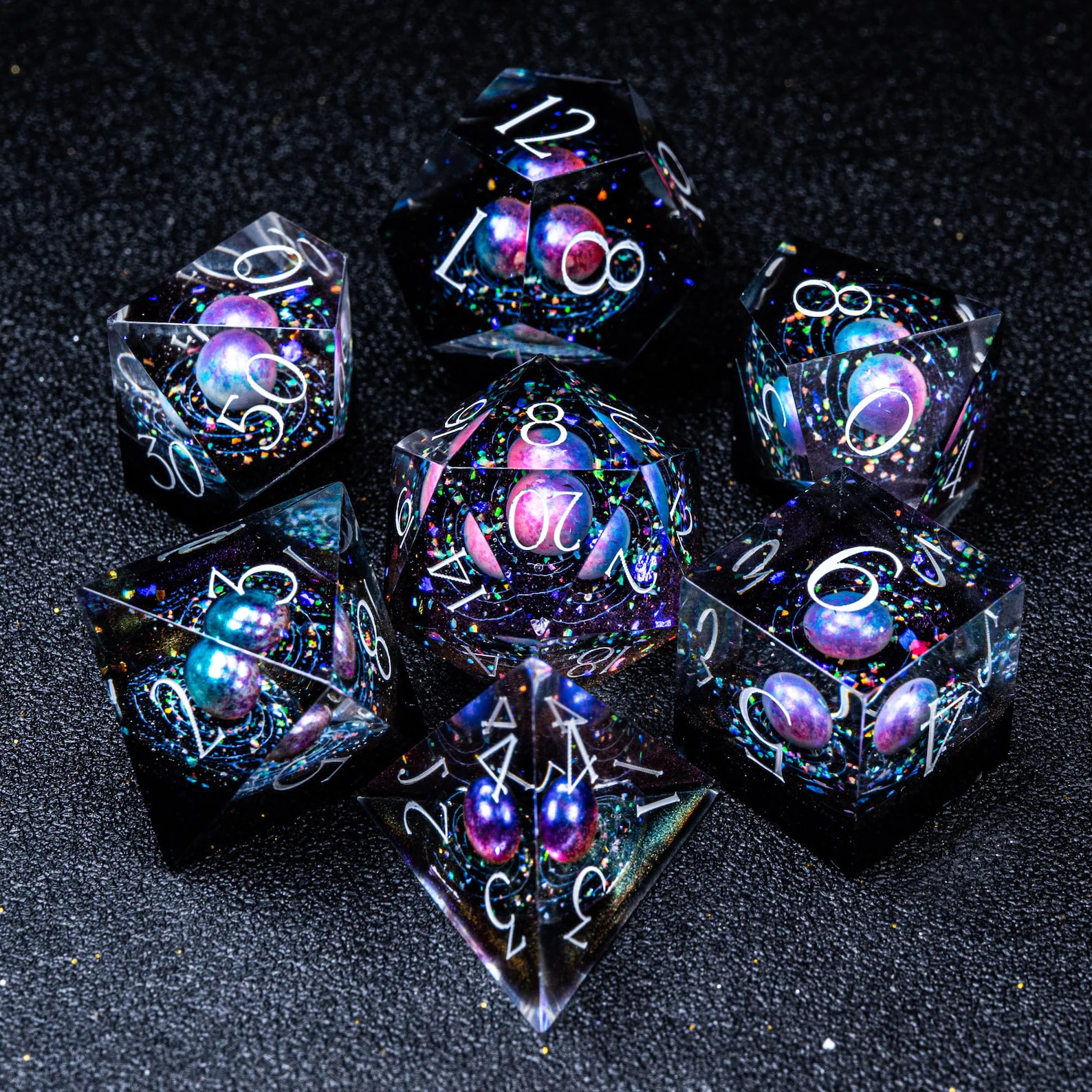 Clear resin dice with galaxies set inside, in jewel tones on black