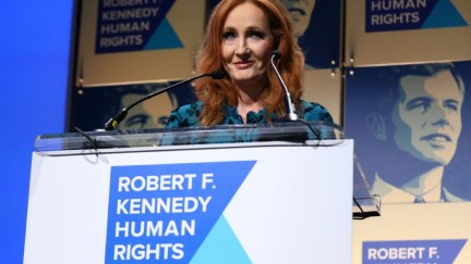 J.K. Rowling accepts an award onstage during the Robert F. Kennedy Human Rights Hosts 2019 Ripple Of Hope Gala. She's smirking.