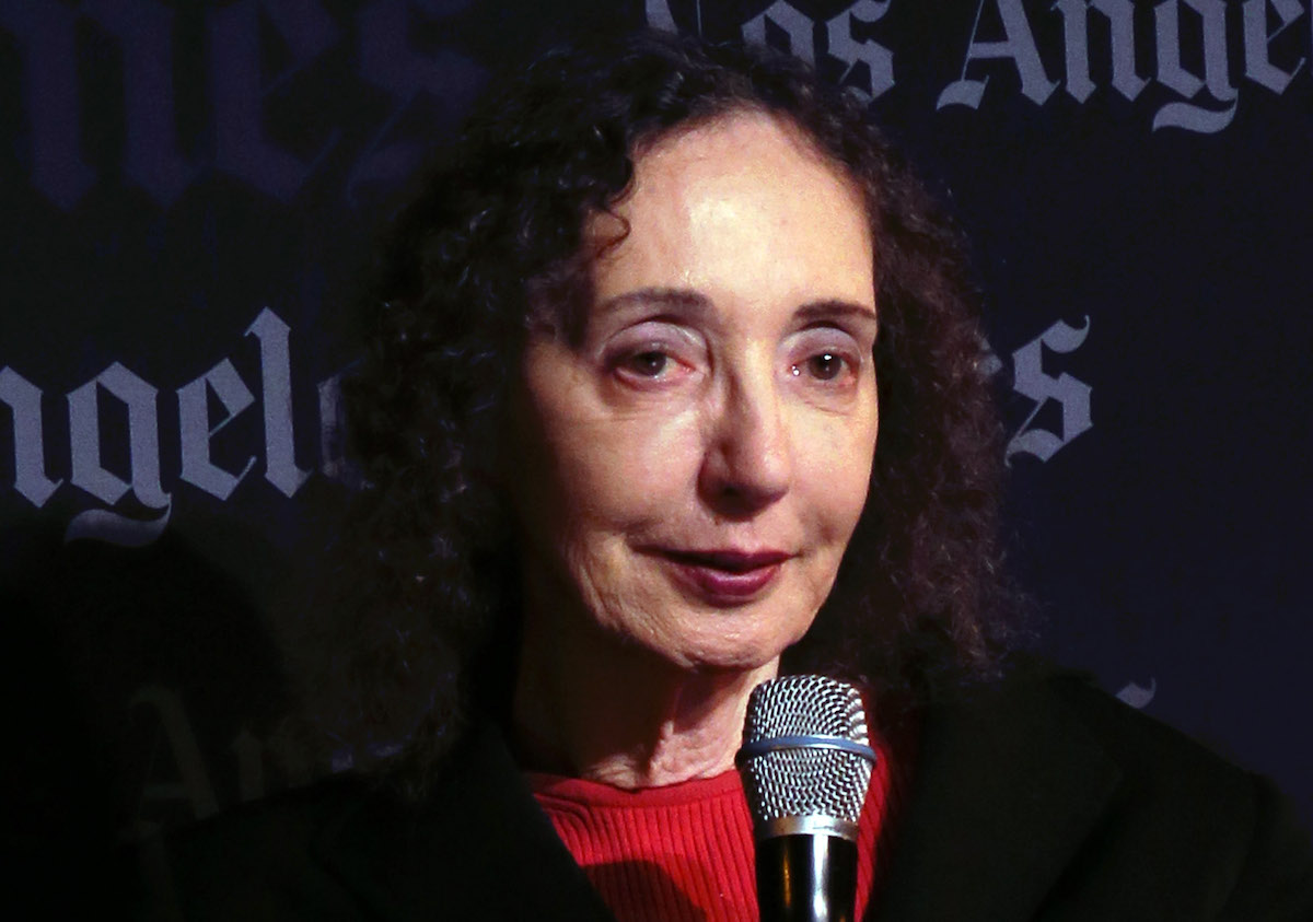 joyce carol oates holds a microphone. The Los Angeles Times logo is visible behind her.