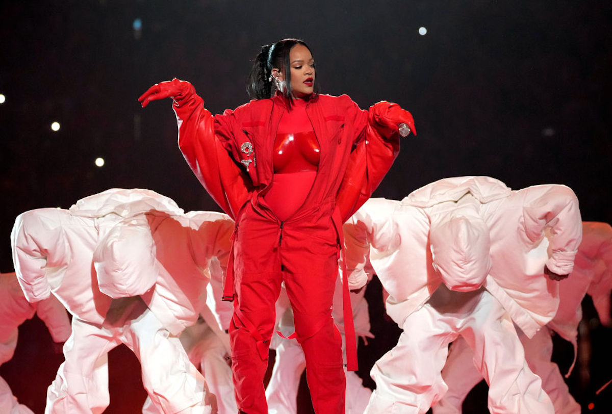Rihanna, dressed in red and surrounded by dancers in white, performs at the 2023 Super Bowl.